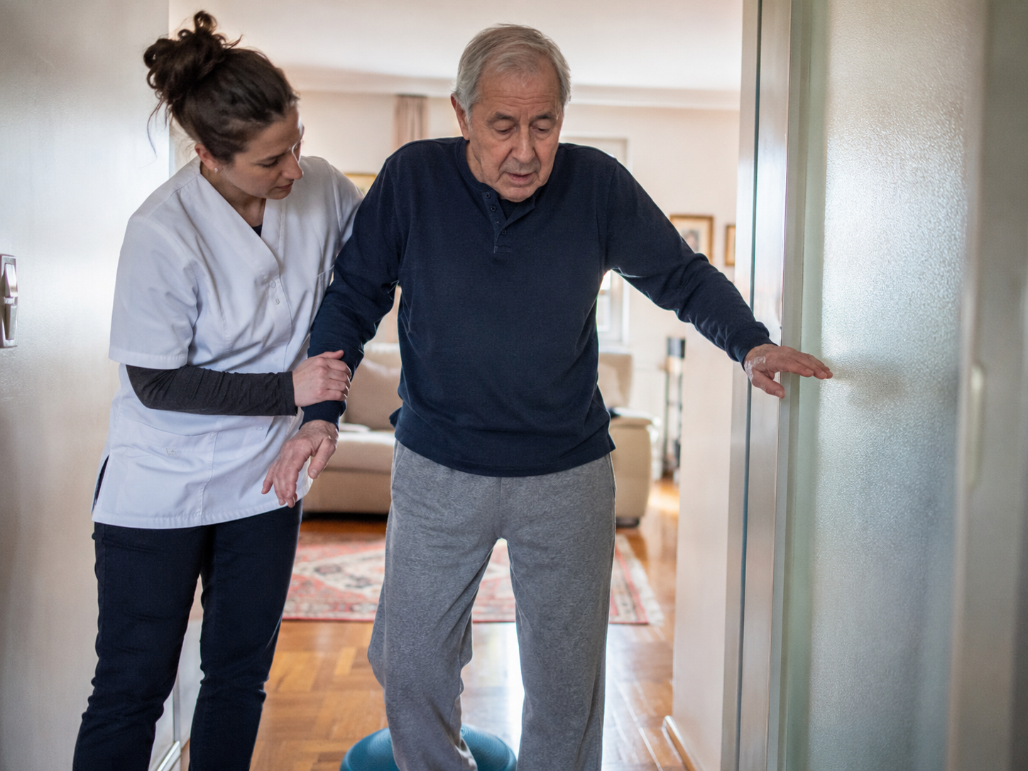 fisioterapeuta realizando exercícios de equilíbrio com idoso com Parkinson em casa